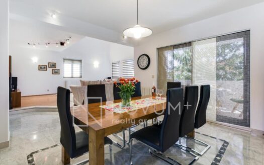 Elegant open-concept living room with a dining area and a modern kitchen, highlighted by custom-made interior details and abundant natural light.